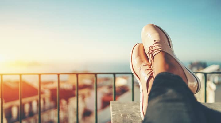 Close up of a woman sitting with their feet up on a balcony