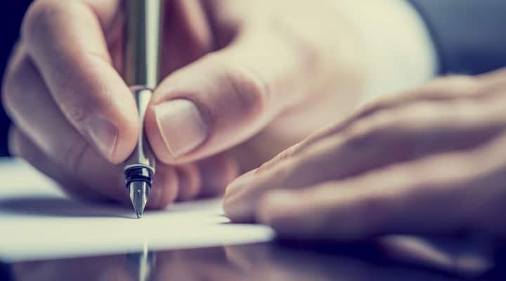 Close up of a hand holding a pen to paper