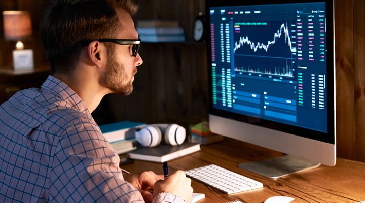 A man looking at graphs and data on a computer screen.