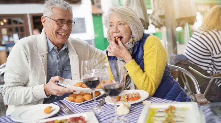 A couple laughing together as they eat al fresco.