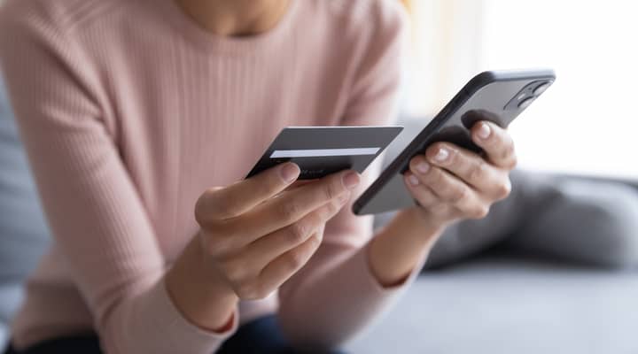 A woman entering bank card details into a phone.