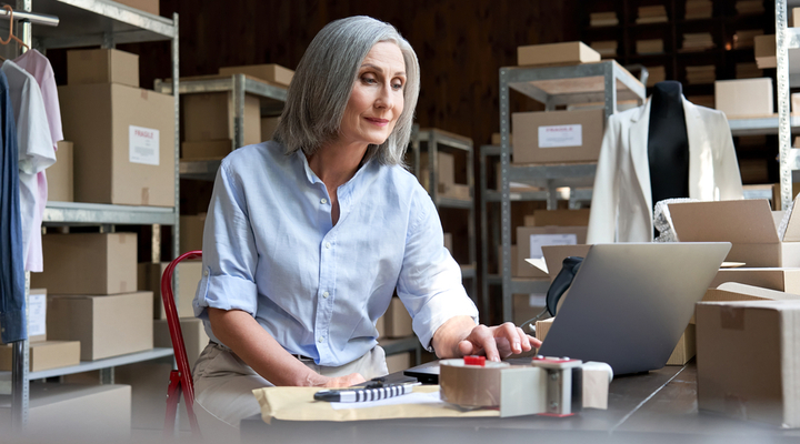 A woman working on a laptop in a warehouse.