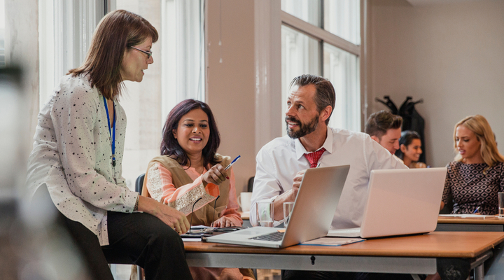 A group of workers gathered around laptops.