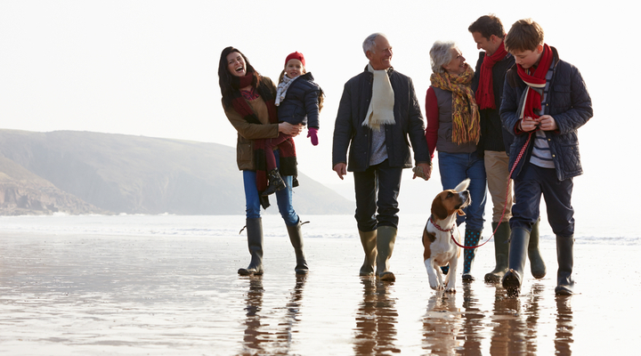 A multi-generation family walking together on a beach.