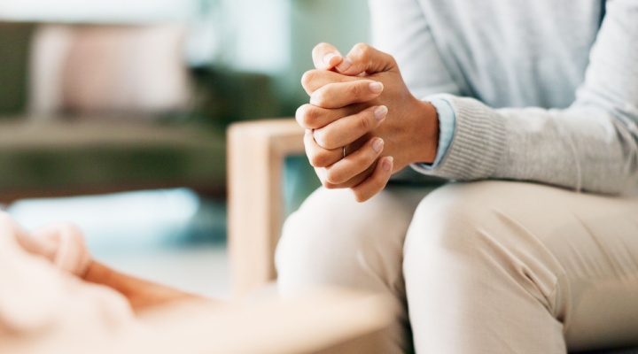 A woman sitting with her hands clasped.
