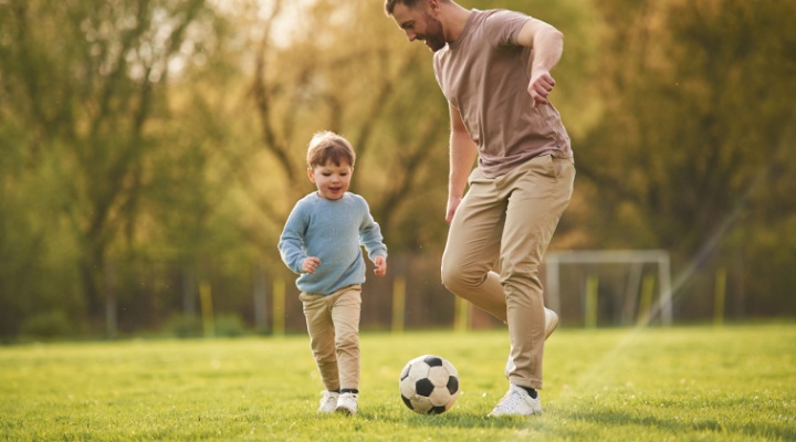 A father playing football with his young son.
