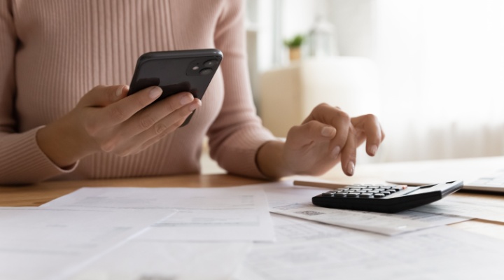A woman using a phone and calculator.