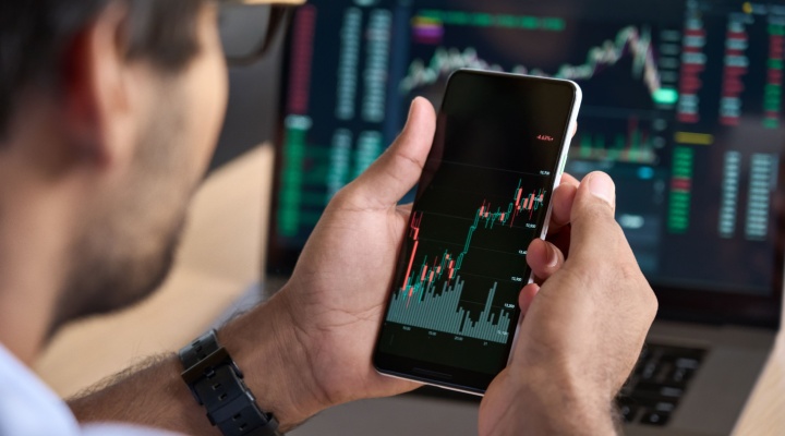 A man looking at a graph showing stock market performance on his phone.