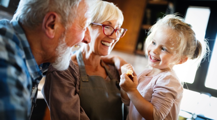 Happy smiling grandparents enjoying time with grandchild at home