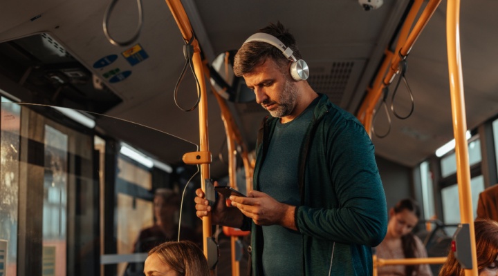 A man travelling on a bus with headphones on.