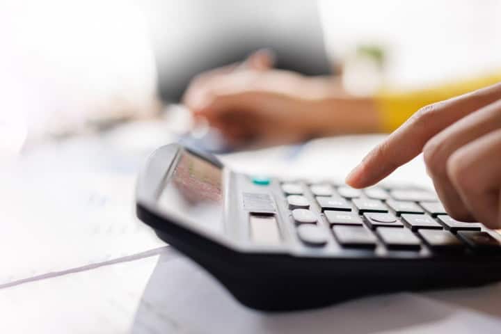 A person using a calculator while reviewing paperwork.