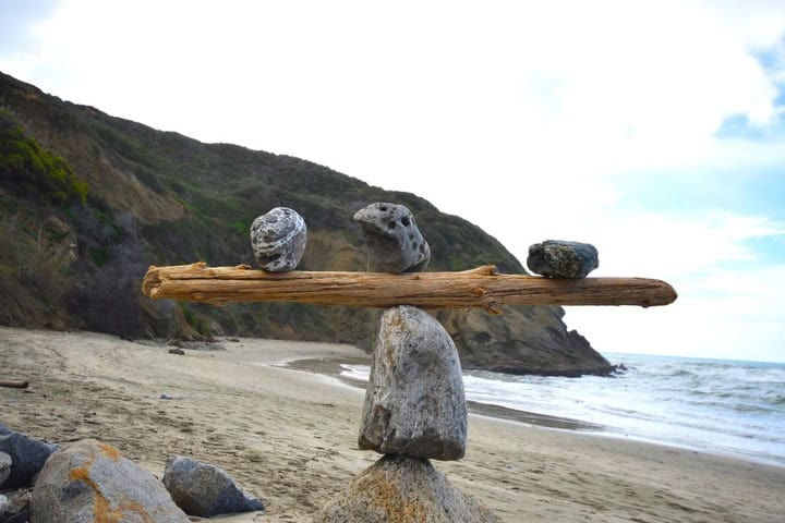 Rocks balancing on log on top of another rock